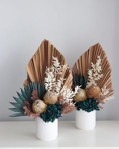 two white vases with flowers and plants in them