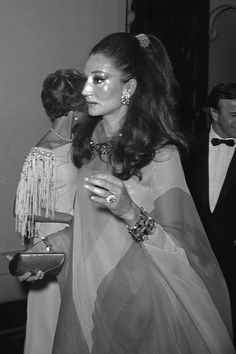 black and white photograph of woman in evening dress at party with man standing behind her