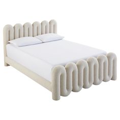 an upholstered bed with white sheets and pillows