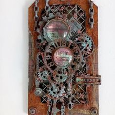 a clock made out of metal gears and chains on a white wall next to a key