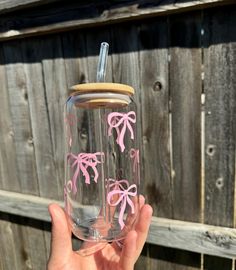 a person holding up a glass with pink bows on it and a corked lid