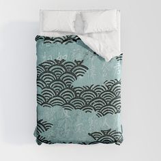 an unmade bed with blue and black designs on the comforter is shown in front of a white wall