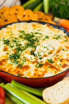 a bowl of cheese dip surrounded by vegetables and crackers