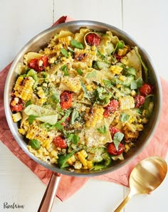 a pan filled with pasta and vegetables on top of a pink napkin