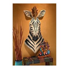 a zebra head mounted to the side of a wall next to a vase and plant