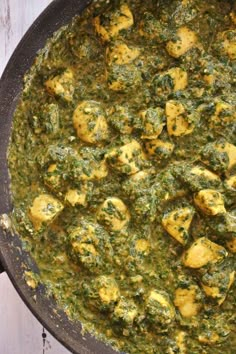 a pan filled with green food on top of a wooden table