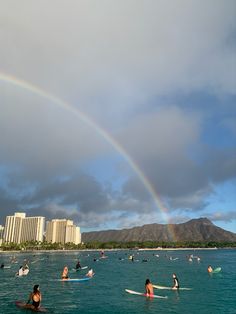 a rainbow is in the sky over some people on surfboards