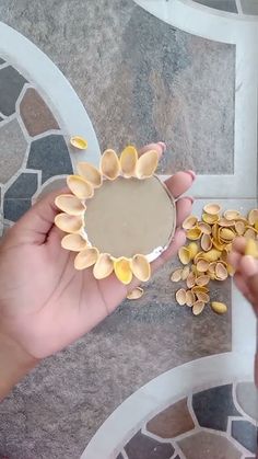 two hands are holding small pieces of food in front of a plate with shells on it