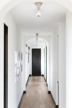 an empty hallway with white walls and wood floors