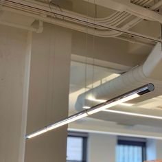 an overhead light fixture is suspended from the ceiling in an office building with large windows