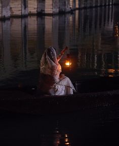 a woman is sitting in a boat on the water at night with her head down