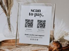 there is a sign that says scan to pay next to a vase with dried grass