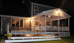 a house with lights on the porch and steps leading up to it's front door