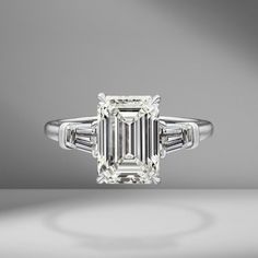 an emerald - cut diamond ring with baguets on the shoulders