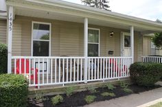 the front porch of a house with red and white striped chairs on it's balconies