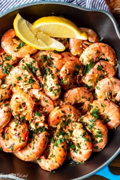 cooked shrimp in a skillet with lemon wedges and parsley