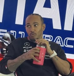 a man holding a pink can in his right hand while sitting on a white chair