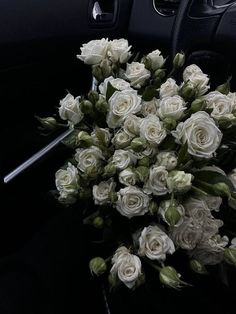 a bouquet of white roses sitting on the dashboard of a car