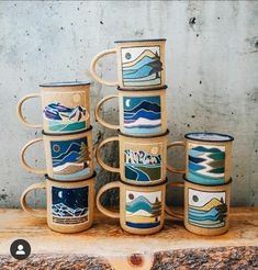 a stack of coffee mugs sitting on top of a wooden table next to a wall