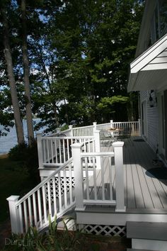 a porch with white railings next to the water