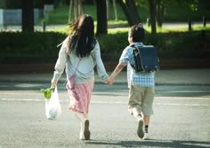 two people walking down the street holding hands and carrying bags with flowers in each hand