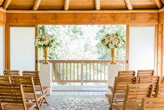 an outdoor ceremony setup with wooden chairs and floral centerpieces on the aisle,