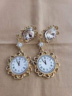 "The earrings have a 7 carat created clear square zircon stone with a 3mm round zircon accents and an \"almost midnight\" time on a clock design.  (not a time piece) 18K gold plated." Diamond Jeweled Earrings For Anniversary, Timeless Evening Earrings With 17 Jewels, Luxury Jeweled Silver Earrings, Formal Jeweled Cubic Zirconia Earrings, Timeless Metal Jewelry For Anniversary, Gold Diamond Crystal Earrings For Formal Occasions, Timeless Gold Diamond Earrings, Formal Gold Diamond Crystal Earrings, Luxury Round Jeweled Earrings