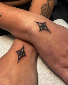 two people with matching tattoos on their legs sitting next to each other, both holding hands