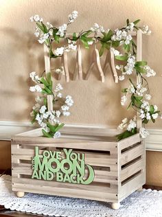 a wooden box with flowers on it and the words love you moon and back written in green