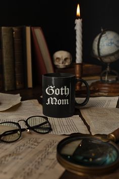 a black coffee mug sitting on top of an open book next to eyeglasses