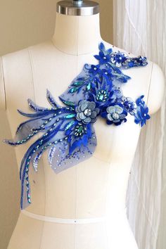 a white mannequin with blue flowers and sequins on it's neck