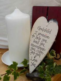 a white candle sitting on top of a table next to a heart shaped wooden sign