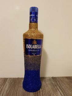 a blue bottle with gold glitter sitting on top of a wooden table