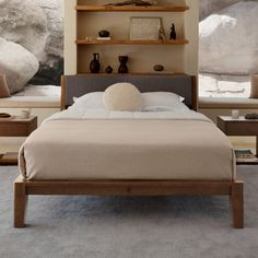 a large bed sitting in a bedroom next to a wall mounted book shelf with books on it