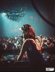 a woman standing in front of a dj set at a concert