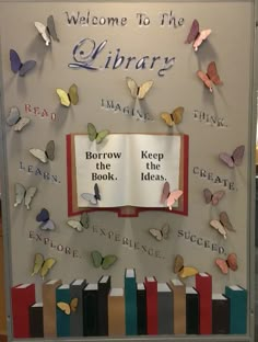 a library display with books and butterflies on the back wall, reading is welcome to the library