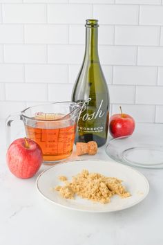 an apple cider, measuring cup and plate with crumbs next to it