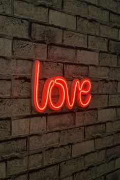 a neon sign that says love on a brick wall