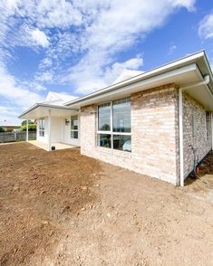 a brick house sitting on top of a dirt field