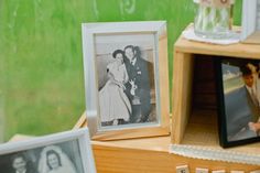 an old photo is sitting on a shelf next to two other pictures and a vase with flowers in it