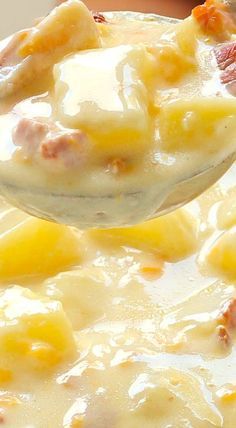 a spoon full of soup with potatoes and ham on it, being held by someone