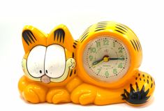 a yellow tiger clock sitting on top of a white table next to a black cat