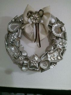 a metal wreath hanging on the wall next to a white ribbon and some silver objects