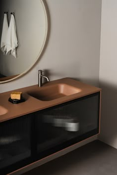 a bathroom sink sitting under a round mirror