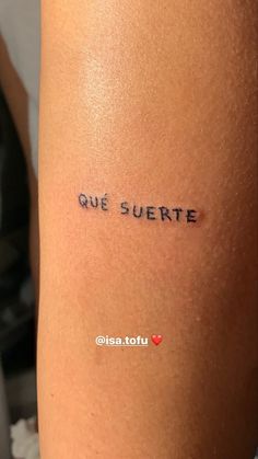 a woman's arm with the words que suerte written in cursive ink