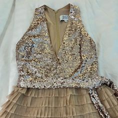 a gold dress with sequins on it is laying on a white sheeted surface