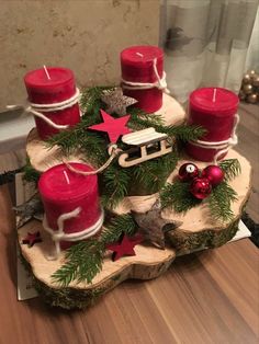 some red candles sitting on top of a tree stump with ornaments around it and one candle in the middle