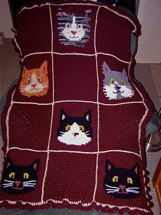 a crocheted blanket with cats on it is sitting on the floor next to a chair