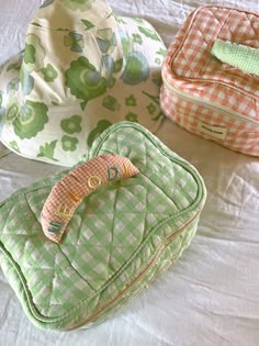 three pieces of luggage sitting on top of a white bed covered in green and orange fabric