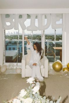 a woman sitting on a chair in front of balloons that spell out the word bride